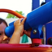 child looking through telescope at playground