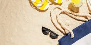 beach sand with sunglasses, sandals and a beach bag