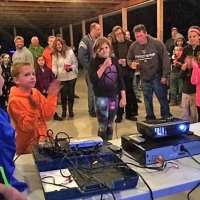 child taking part in karaoke with a crowd around her