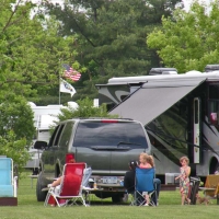 family at campsite sitting outside of camper