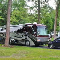 gray and black camper with car at campsite