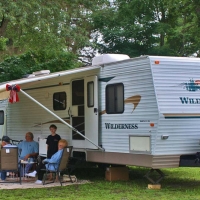 family sitting outside of camper during the day